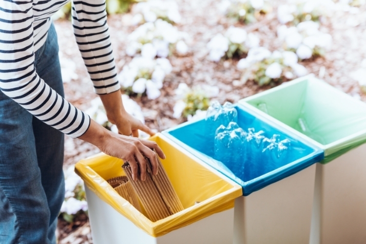 Woman placing used bottles and other trash in dustbins